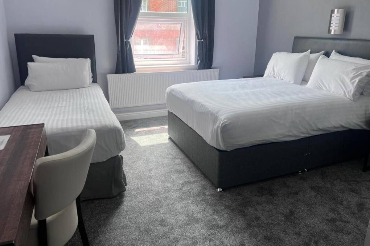 Une chambre d’hôtel avec deux lits simples, un bureau et une chaise.