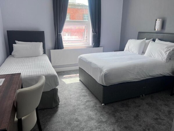 A hotel room with two single beds, a desk, and a chair. - Dancenter East Midlands Airport (Derby)