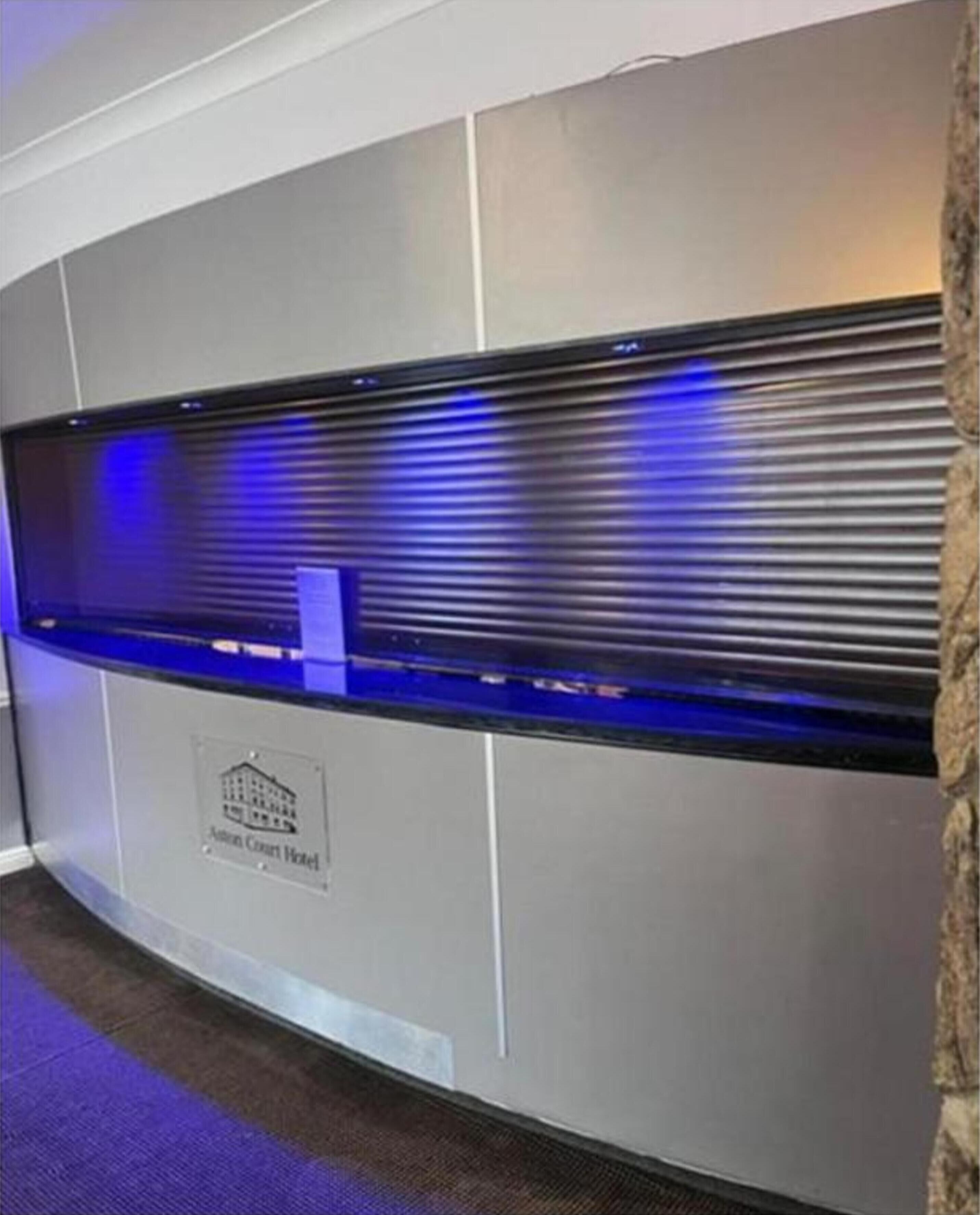 A reception desk with a blue-lit display and a plaque indicating the location as the "Antony Court Hotel."
