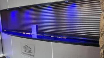 A reception desk with a blue-lit display and a plaque indicating the location as the "Antony Court Hotel."