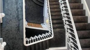 Eine Wendeltreppe mit spiegelnder Oberfläche und einem Geländer mit floralem Muster.