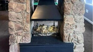 Ein Steinkamin mit schwarzem Sims und einem Feuer darin.