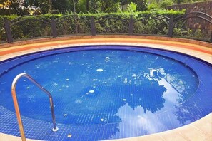 Une piscine circulaire dont la surface est recouverte de carreaux bleus et qui est équipée d’une échelle en métal.