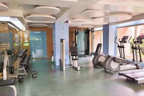 Une salle de sport équipée de machines de cardio, de poids et d’haltères.
