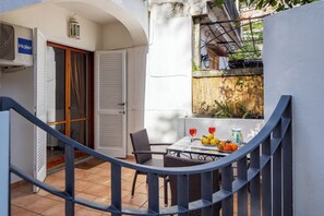 A small outdoor dining area with wicker chairs and a table set with fruits and glasses. - Casa Simona (Positano)