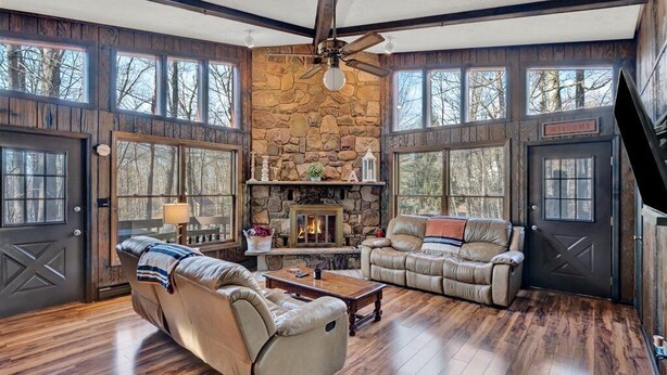 A spacious living room with a stone fireplace, leather sofas, and large windows. - The Alpine Arena (Clifton Township)