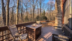 An outdoor deck with a fire pit, wooden benches, and a stone wall. - The Alpine Arena (Clifton Township)
