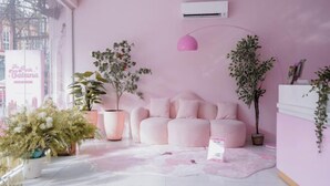 Una stanza dai toni rosa con un divano, piante in vaso e un tappeto.
