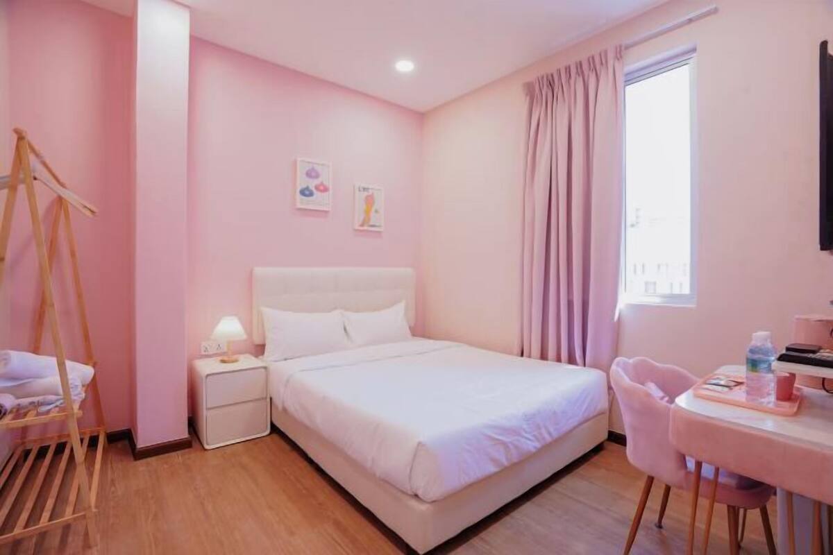 A bedroom with a bed, bedside table, lamp, and a chair.