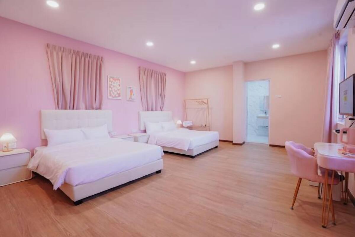 A hotel room with two beds, a small table, and a chair.