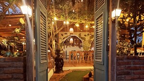 An indoor pathway leading to a dining area with wooden furniture and decorative lighting. - Café Madame (Puerto Lopez)