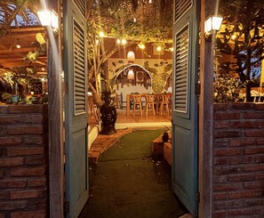 An indoor pathway leading to a dining area with wooden furniture and decorative lighting. - Café Madame (Puerto Lopez)