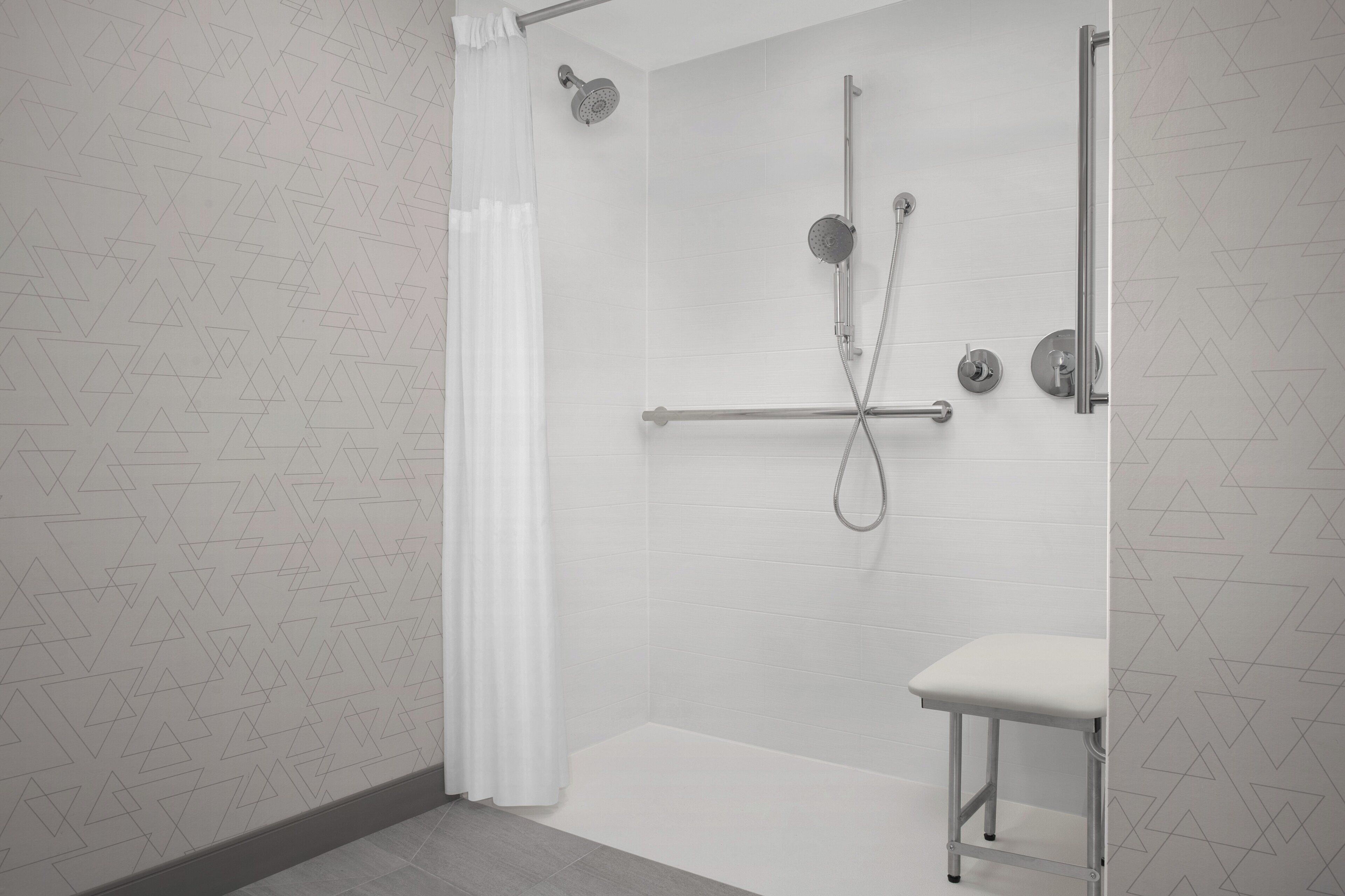 A modern bathroom with a shower, a toilet, and a small bench.