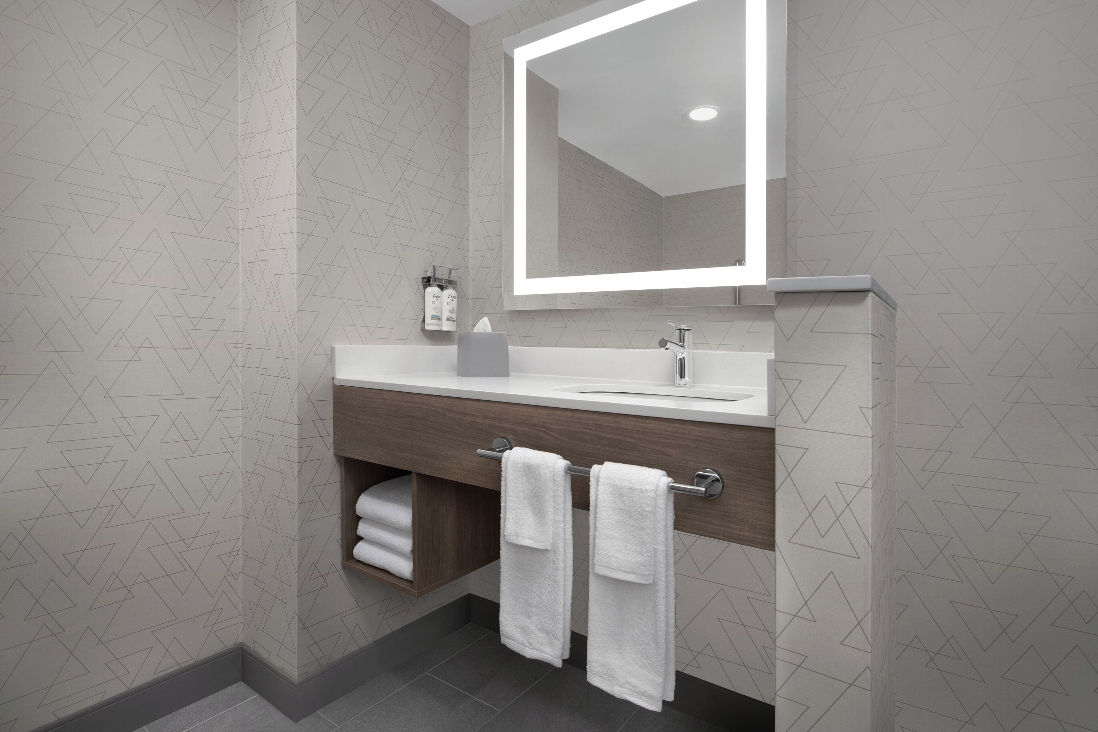 A modern bathroom with a large mirror, a wooden vanity, and a towel rack.