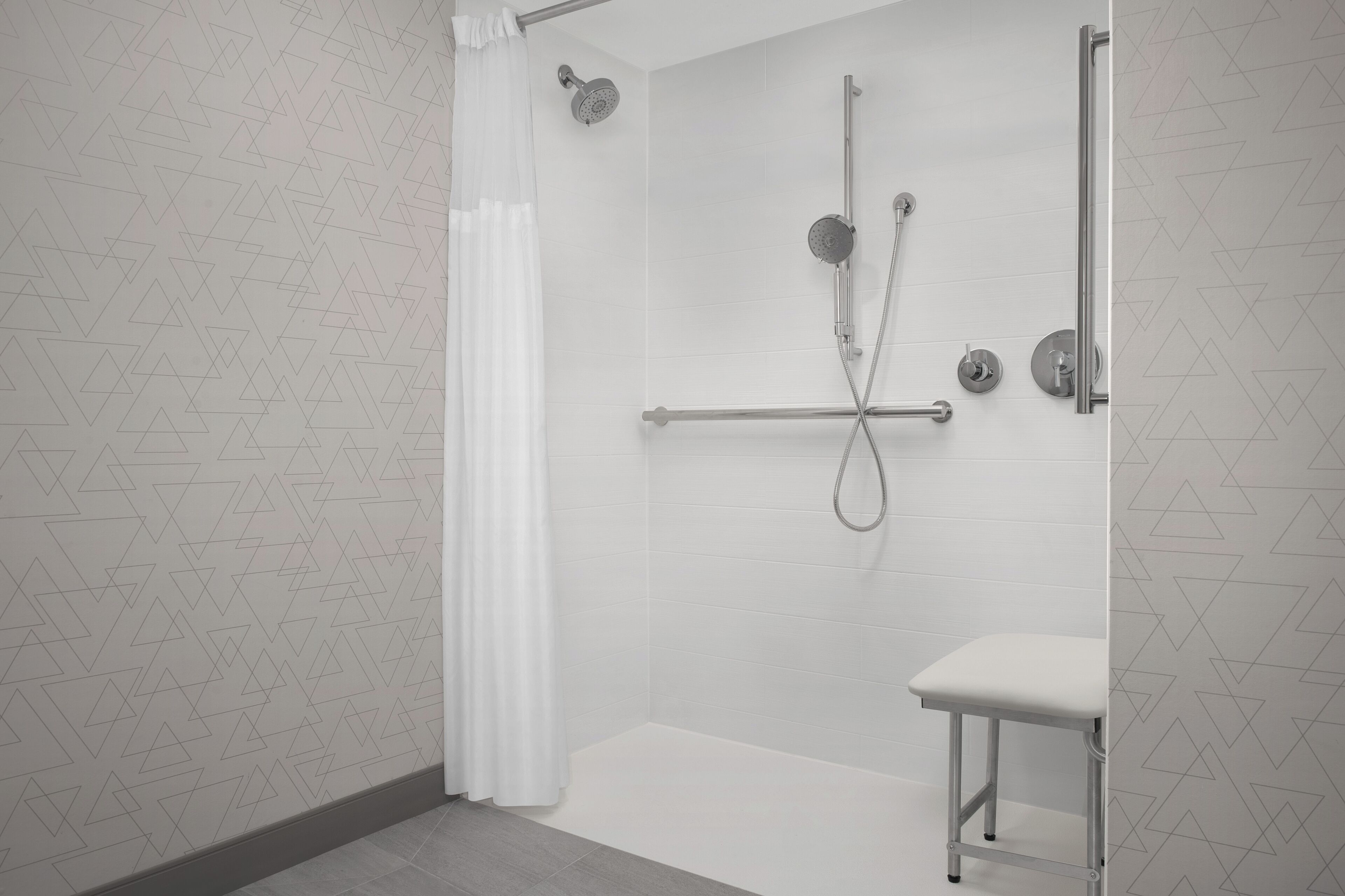 A modern bathroom with a shower, a toilet, and a bench.