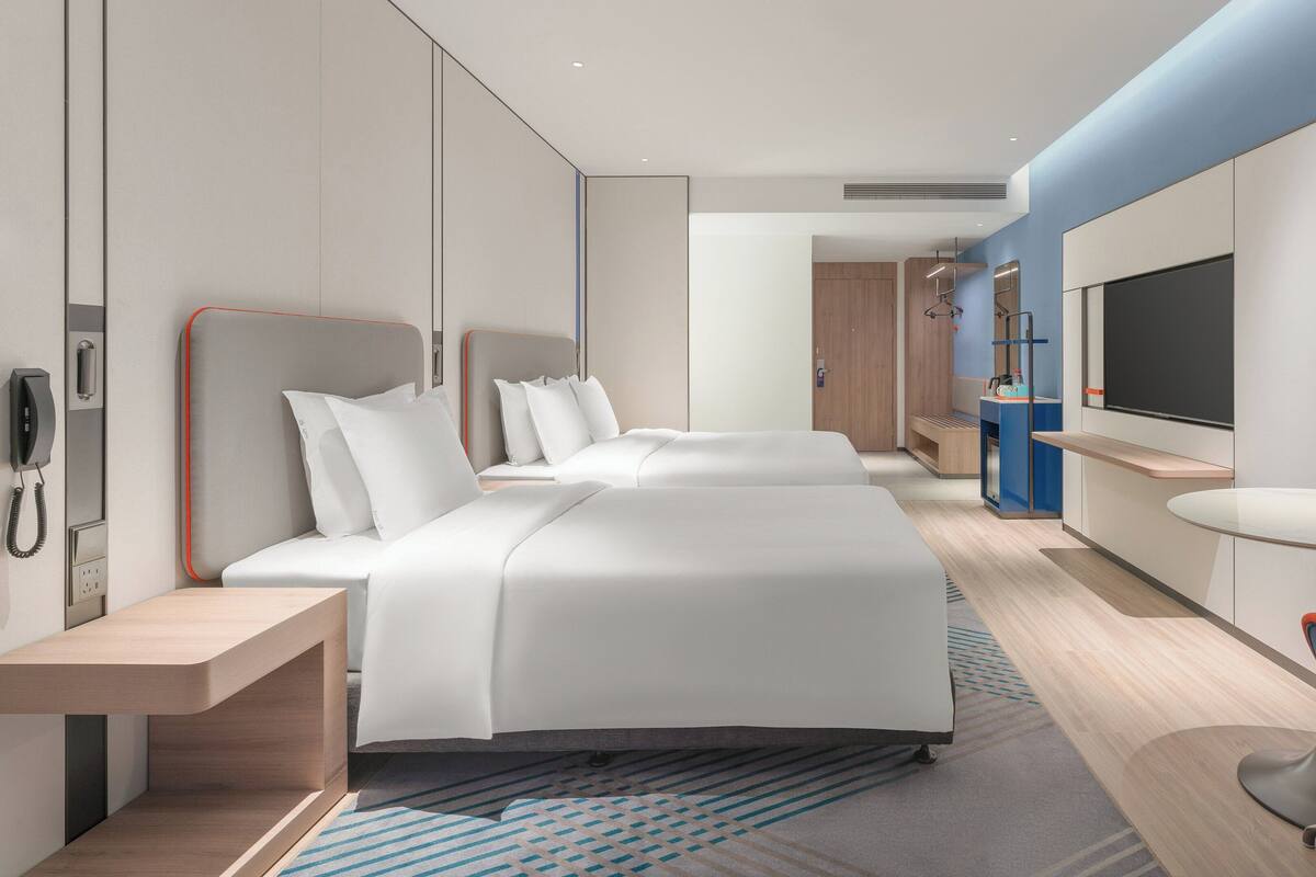 Une chambre d’hôtel moderne équipée de deux lits, d’un bureau, d’une chaise, d’une télévision et d’un téléphone.