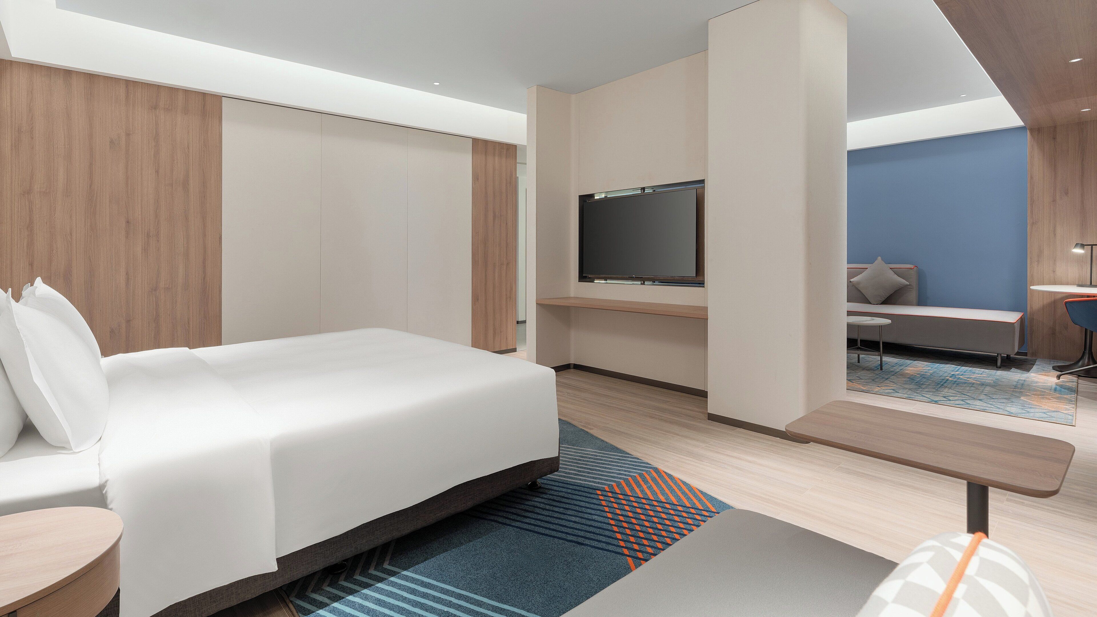 Une chambre d’hôtel moderne équipée d’un lit, d’une télévision, d’un bureau et d’un coin salon.