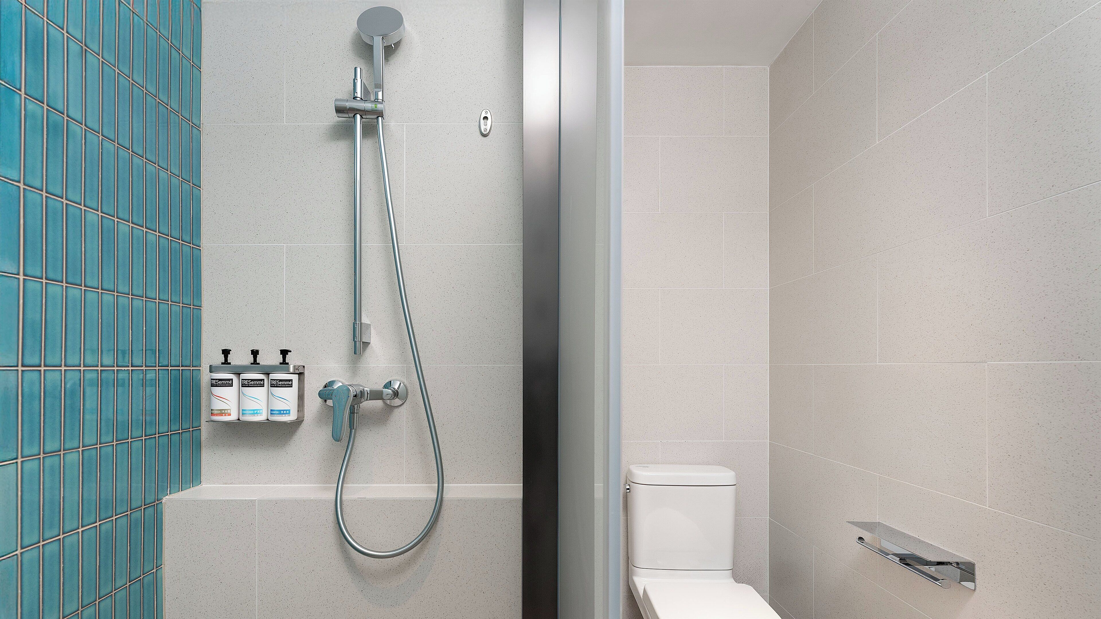 Un bagno moderno dotato di doccia, WC e asciugatore a mano.