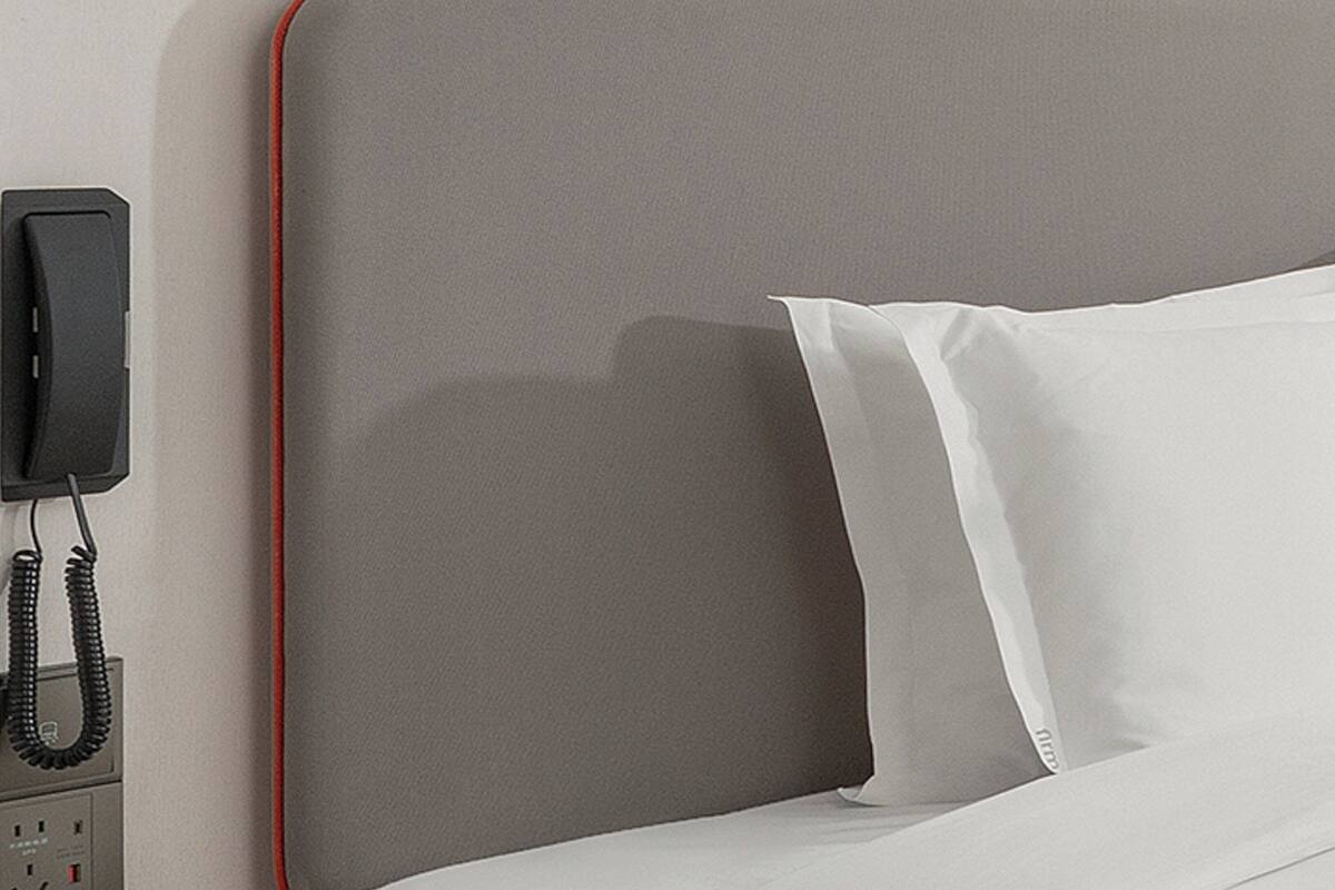 Un lit avec des oreillers blancs et une tête de lit grise.
