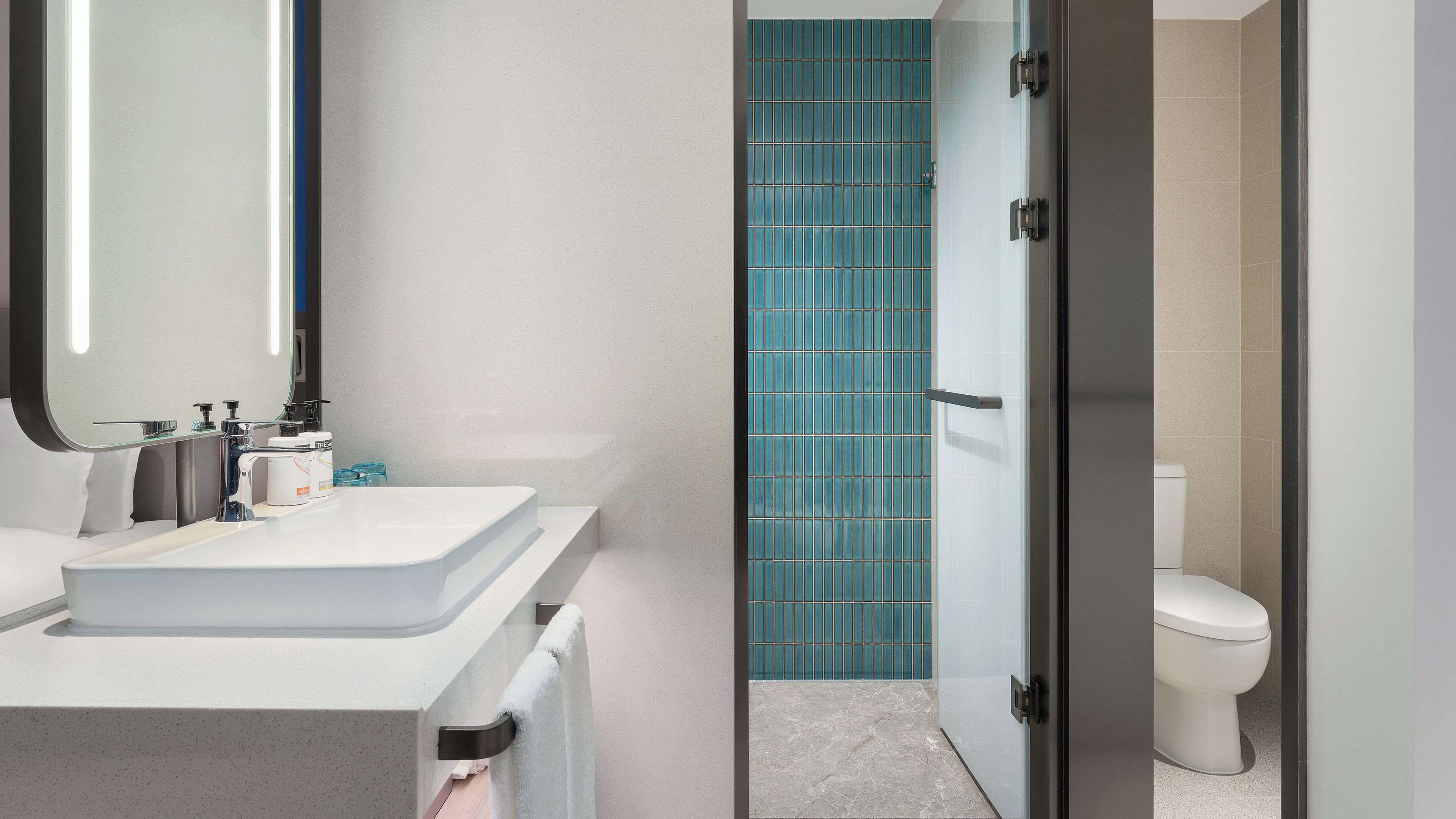 A modern bathroom with a white sink, mirror, and toilet.