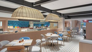 A modern restaurant with a bar area, seating, and a kitchen in the background. - Holiday Inn Express Puer Simao by IHG (Pu'er)
