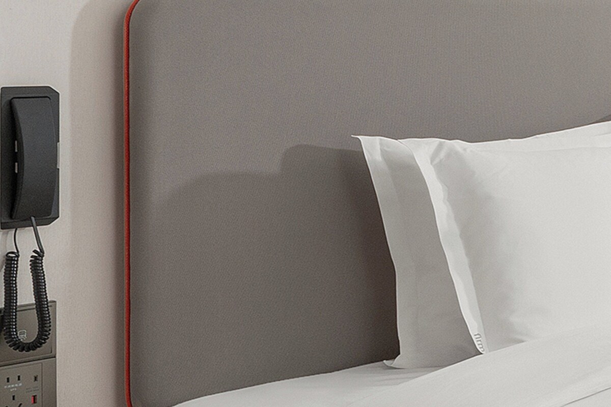 A bed with white pillows and a grey headboard.