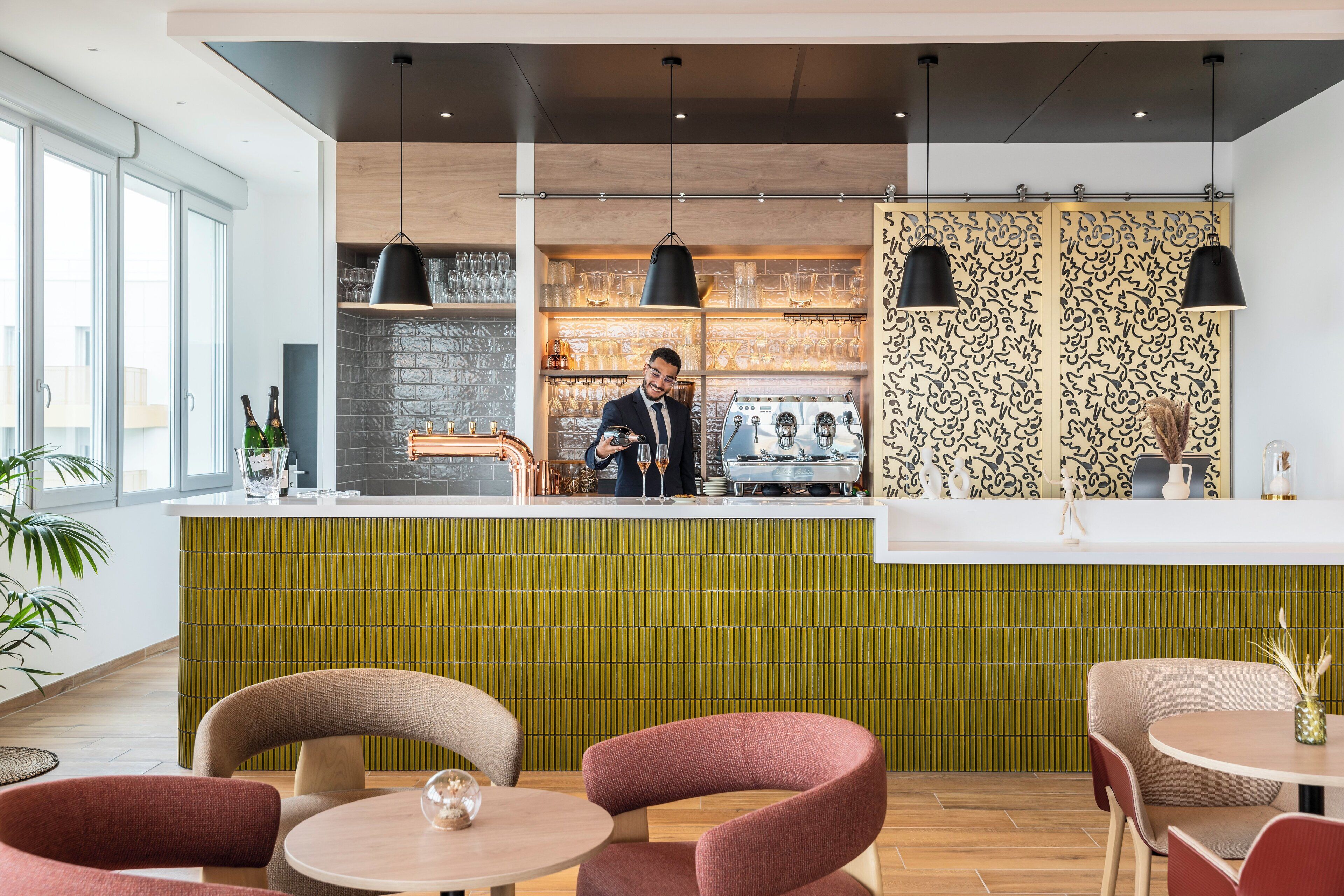 Een modern restaurantinterieur met een bar, zitplaatsen en een kok achter de toonbank.