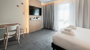 A hotel room with a bed, a desk, a chair, a TV, and a window with curtains. - Holiday Inn Express and Suites Reims Rives De Vesle by IHG (Reims)