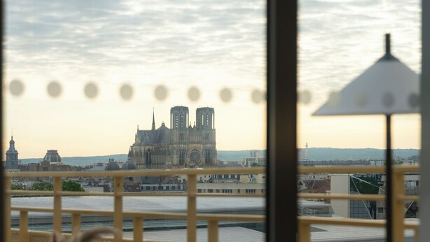 Blick vom Balkon auf einen Fluss mit einer historischen Kathedrale im Hintergrund.