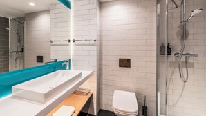 A modern bathroom with a large white sink, a bathtub, a toilet, and a glass-enclosed shower area. - Holiday Inn Express and Suites Reims Rives De Vesle by IHG (Reims)