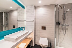 A modern bathroom with a large white sink, a bathtub, a toilet, and a glass-enclosed shower area. - Holiday Inn Express and Suites Reims Rives De Vesle by IHG (Reims)