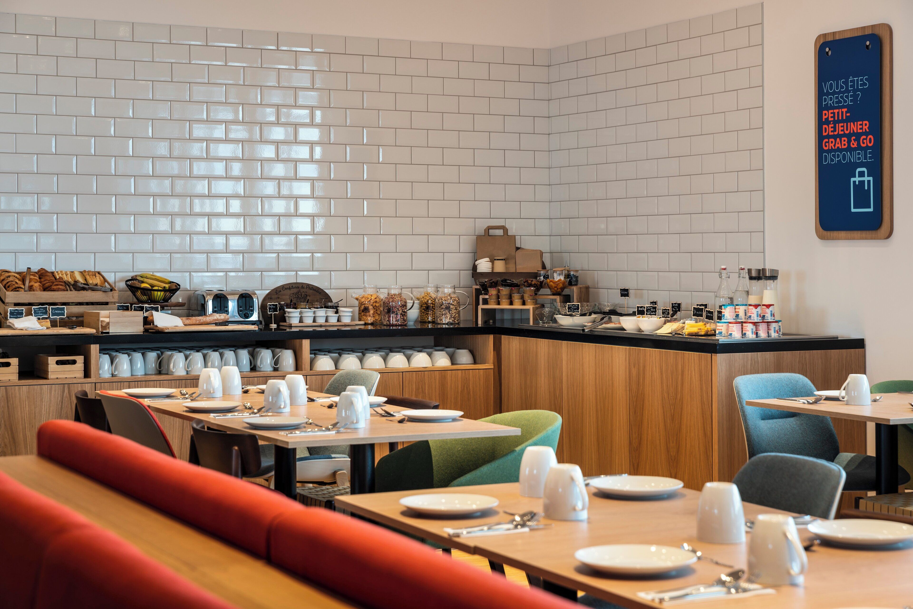 Un restaurante moderno con paredes de azulejos blancos, mostradores de madera y mesas y sillas ordenadas.