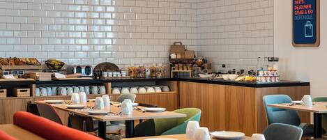 A modern restaurant with white tiled walls, wooden counters, and neatly arranged tables and chairs.