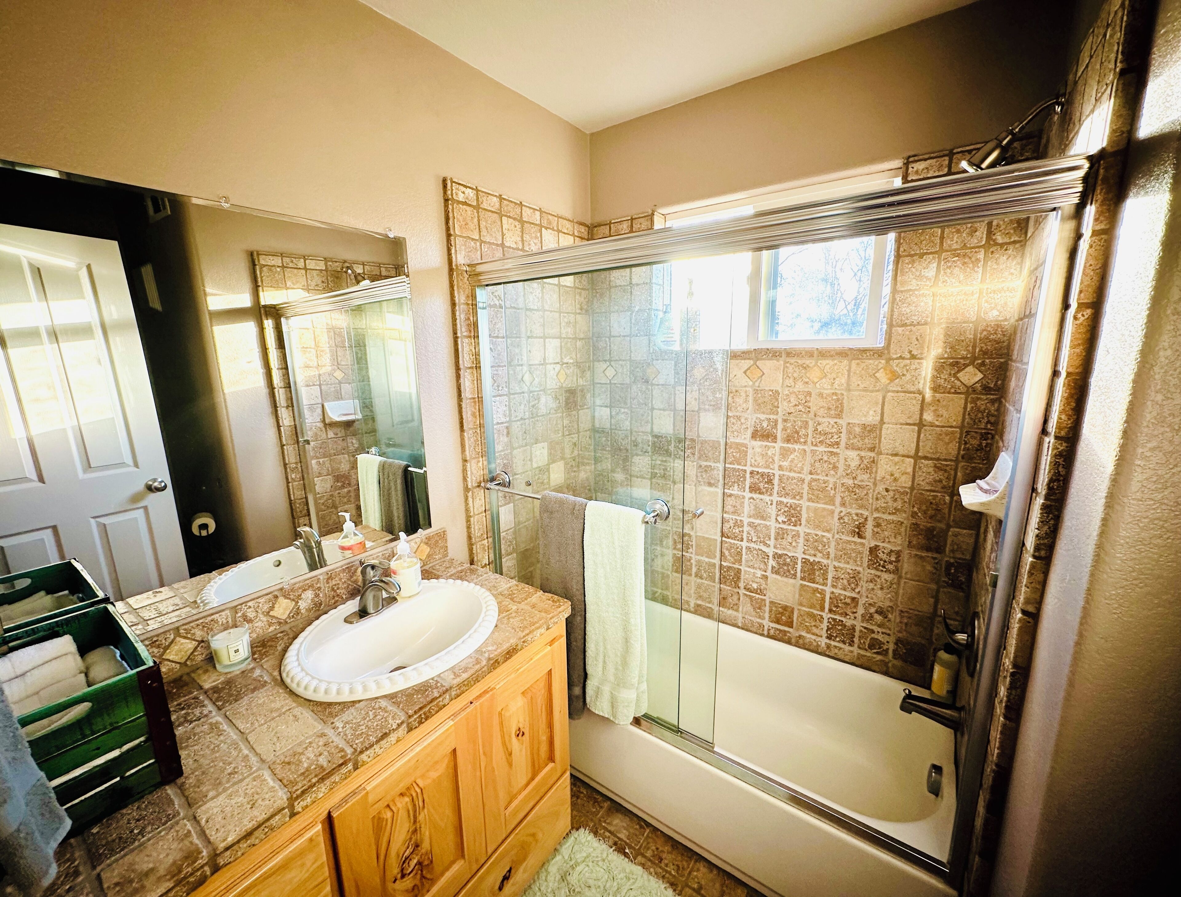 A bathroom with a glass-enclosed shower, a white sink, and a wooden vanity.