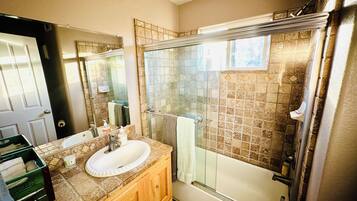 A bathroom with a glass-enclosed shower, a white sink, and a wooden vanity.