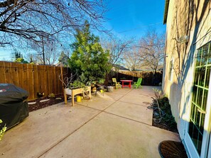 A backyard with a wooden deck, a red table, and green chairs. - Charming & Central 2200 sq. feet house in Davis walking distance to everywhere (Davis)