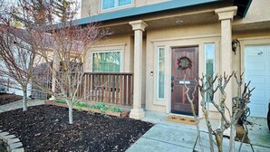 A two-story residential building with a beige exterior, a front porch, and a garage.