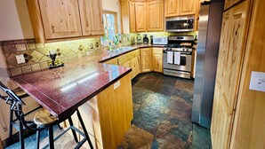 A kitchen with wooden cabinets, a granite countertop, a stainless steel refrigerator, and a built-in oven.
