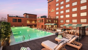 A hotel with a swimming pool, outdoor seating, and a brick facade. - Holiday Inn Gurgaon NH8 by IHG (Gurugram)