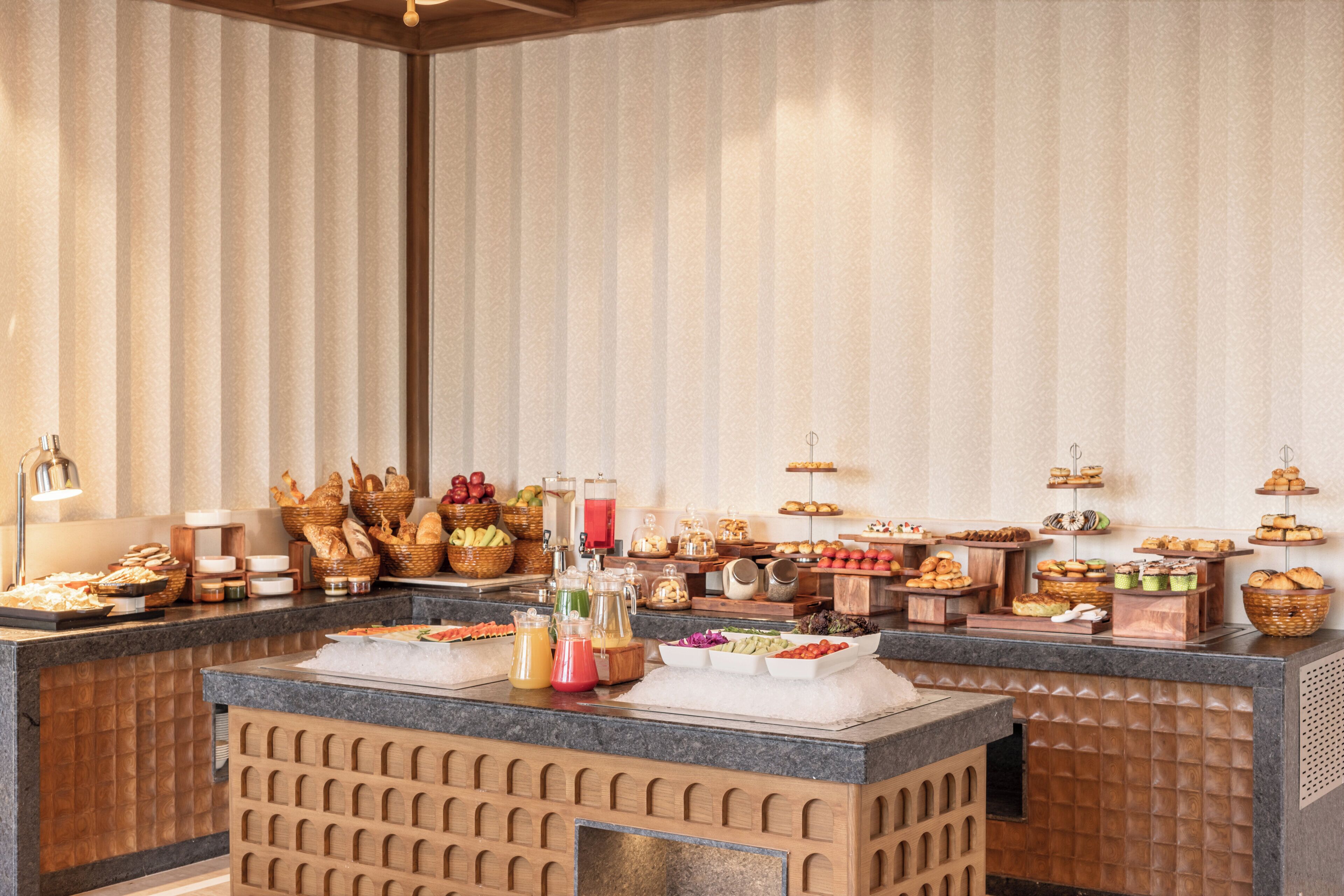A buffet with various food items and beverages, including fruits, pastries, and drinks.