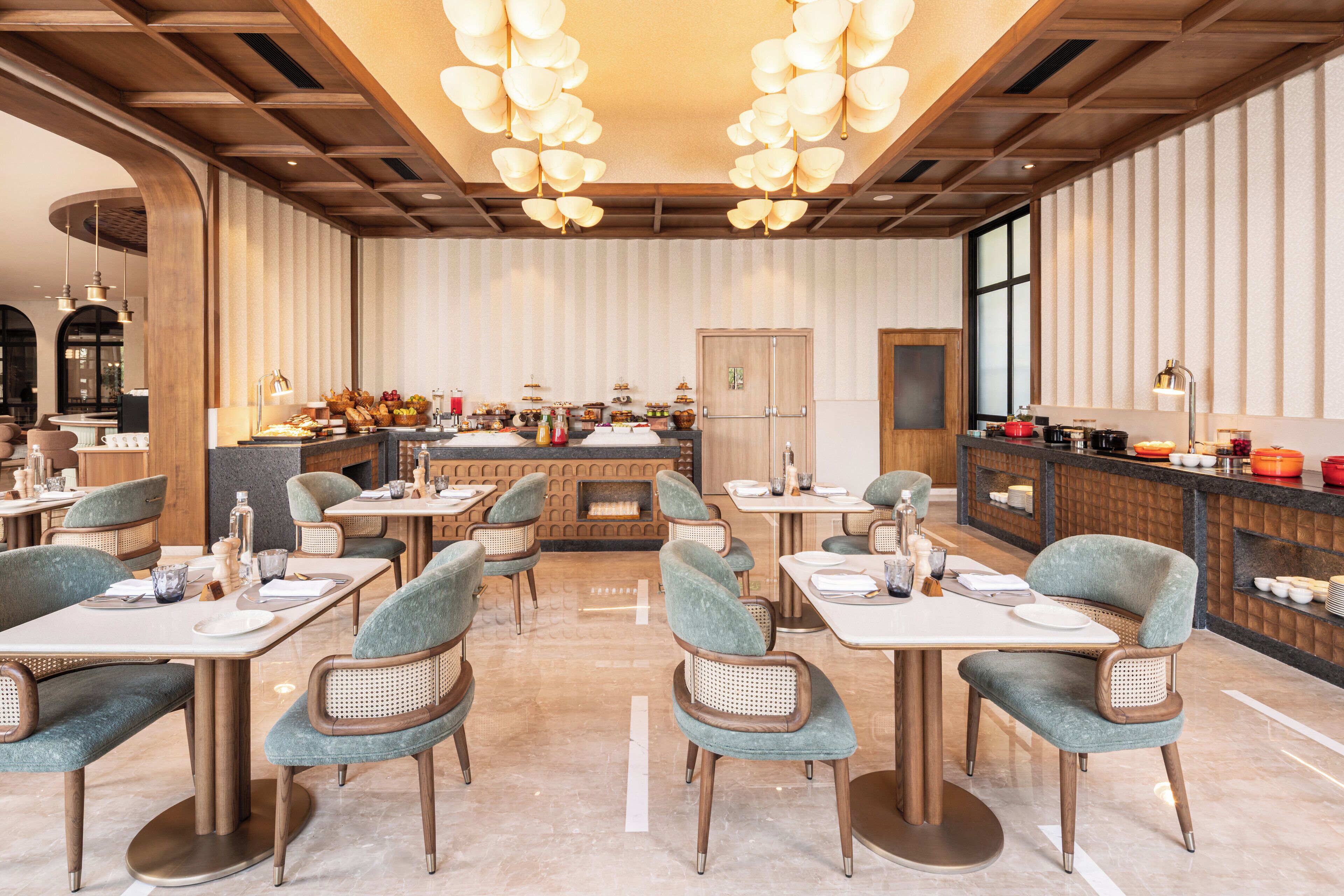 A modern restaurant with round tables and cushioned chairs, a bar area with a counter, and a large window providing a view.