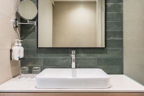 A bathroom with a white sink, a mirror, and a bottle of hand soap on the counter.