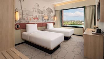 A hotel room with two beds, a large window with a view, a mural on the wall, and a desk with a lamp.