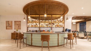 A bar area with a curved counter, multiple stools, and a variety of bottles and glasses. - Holiday Inn Gurgaon NH8 by IHG (Gurugram)