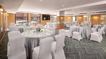 A conference room with round tables, white chairs, and a large screen.