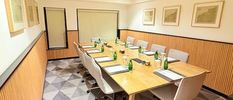 Un salón de conferencias con una larga mesa, sillas y una pantalla para proyector.