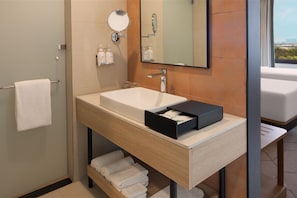 A modern bathroom with a large sink, mirror, and towel rack.