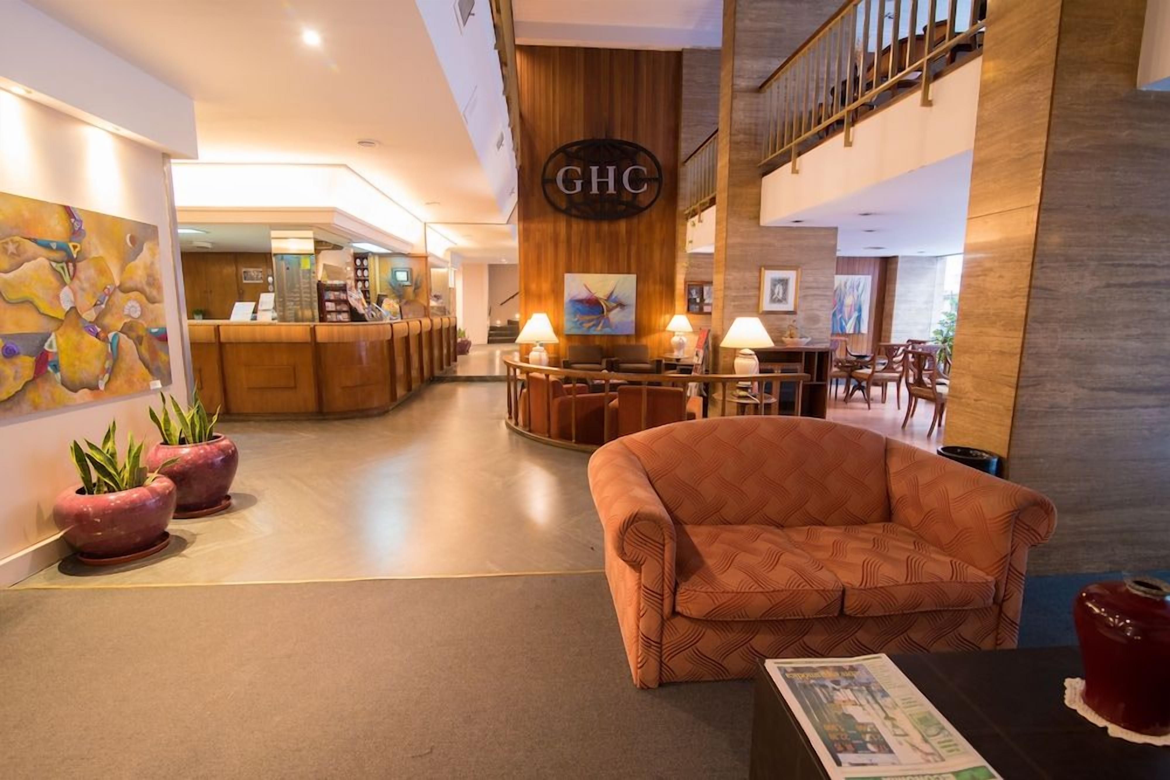 A hotel lobby with a reception desk, a sofa, and a staircase.