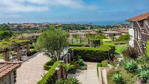 Área residencial com vista para o oceano, piscina e jardim bem cuidado.