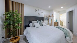 Quarto com cama, mesa de cabeceira e planta em vaso.
